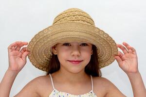 Portrait of caucasian smiling child holding straw hat on head of 6 7 years looking at camera on white background photo
