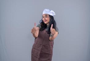 a woman in an apron and chef hat giving the thumbs up photo