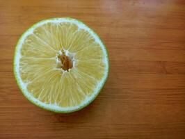Fresh Lime Slice on Table. A fresh lime slice sits on a wooden table, revealing its juicy segments and natural texture. photo
