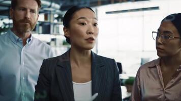Team of professionals engaged in strategic discussion using a glass board in a bright modern office, showcasing teamwork, planning, and collaboration in a creative work environment. video