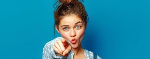 Playful female pointing across screen studio portrait blue background. photo