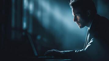 Businessman typing on laptop in dimly lit room photo
