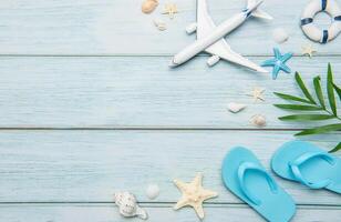 Planning summer vacation with airplane, flip flops and seashells on wooden background photo