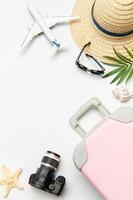 Pink suitcase, camera, sunglasses and airplane model suggesting summer planning photo