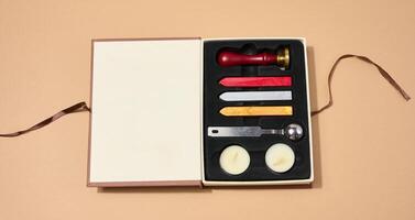 Wax seal kit including wax sticks, spoon, candles, stamp and sealed scroll placed on a neutral background. photo