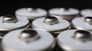 Close-Up View of Silver Button Cell Batteries Lined Up in a Soft Focus Industrial Environment video
