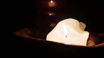 Softly Flickering White Candle Flame Creating Warm Glow in Dimly Lit Rustic Space video