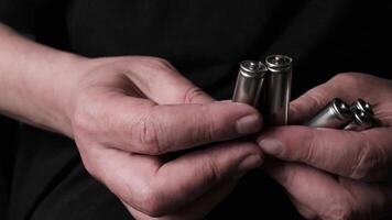 Close-up of Hands Handling AA Batteries for Charging in a Dark Minimalist Environment video