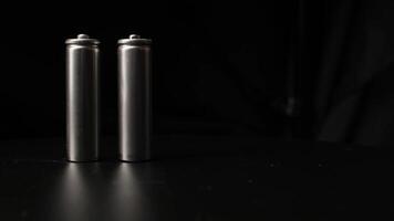 Close-up of Hand Arranging Metallic Batteries on a Black Surface in Dim Lighting Environment video