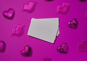 Set of blank white business cards surrounded by pink decorative hearts and lips on a bright pink background photo