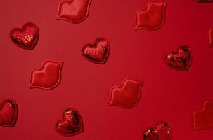 Red decorative hearts and lips randomly placed on a bright red background photo