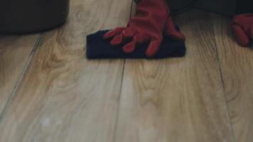 A person wearing red gloves and a blue rag on a wooden floor video