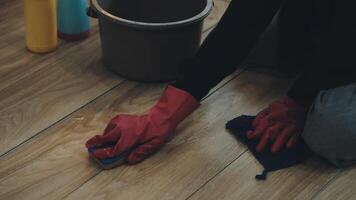A person wearing red gloves and a red glove cleaning a wooden floor video