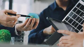Business people working on laptops and tablets with a globe video