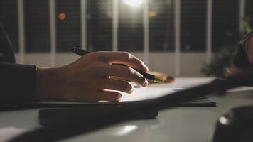 A person writing on a piece of paper at night video
