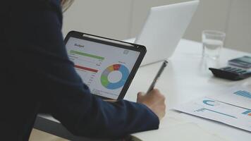 A businesswoman using a tablet to view financial data video