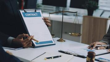 A group of business people are sitting at a table with a contract video