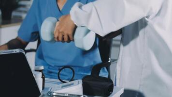 A doctor is working on a laptop while holding a dumbbell video