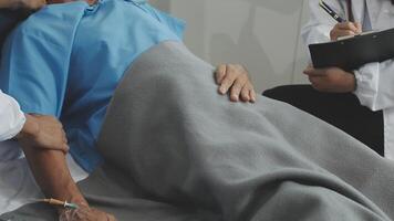 A doctor is holding a patient's hand while another doctor is looking at the patient video
