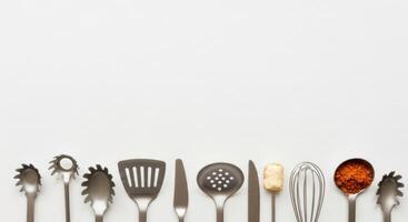 Kitchen Utensils Bordering White Space with Pasta Spoon, Spatula, Knife, Whisk, and Spice photo