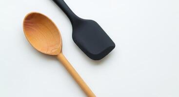 Wooden spoon and black spatula on a white surface, kitchen utensils, cooking tools photo
