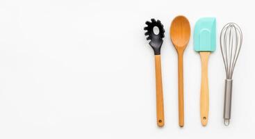 Culinary tools Spaghetti server, wooden spoon, blue spatula, and whisk on white photo
