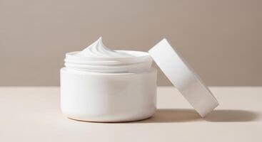 Creamy white moisturizer in open jar with lid resting on neutral surface photo