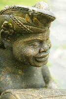 The face of a carved stone statue wearing a typical Balinese head covering udeng in close up mode photo