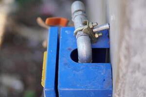 A small pipe leading into a water flow control box in a building. photo