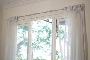 A minimalist white box shaped window with curtains open during the day photo