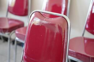 Red chairs lined up in a room during the day photo