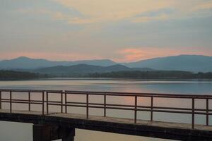 The concrete walkway into the water reservoir with the horizontal line of the mountains during the sunset photo