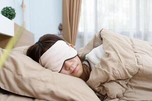 sian young girl sleeping in bed room with an eye mask on her face, Blanket covering the entire scene of sleep and relaxation photo