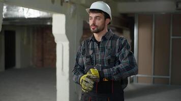 Caucasian builder engineer man wearing gloves foreman uniform start working on construction site building technician master handyman repairman architect engineering job safety rules architecture build video