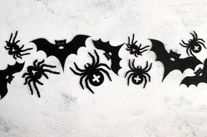 Halloween party card or invitation with place for text. Black spiders and bats flat lay on concrete background photo