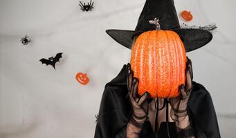 halloween background with unrecognizable with hiding her face behind pumpkin.Banner with place for text photo