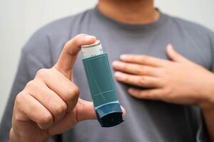 Asthma and chronic obstructive pulmonary disease COPD, Asian young man using metered dose inhaler MDI. photo