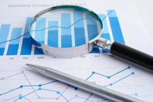 Magnifying glass on spreadsheet and graph paper. Financial development, Banking Account, Statistic, Investment Analytic research data economy, Business. photo