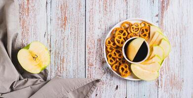 Crispy green apples and pretzels with miso caramel sauce on a plate top view web banner photo