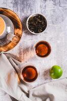 Home brewed earl grey tea in cups and teapot on table top and vertical view photo