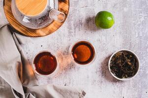 Earl Grey tea with bergamot in cups and teapot on table top view photo