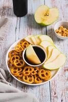 Crispy green apples and pretzels with miso caramel sauce on a plate on a table vertical view photo