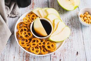 Crispy green apples and pretzels with miso caramel sauce on a plate on a table photo