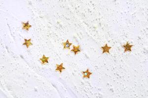 Gold star sequins on white texture creating a festive and elegant abstract pattern. photo
