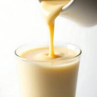 Pouring Creamy Liquid Into Glass on White Background photo