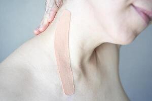 Close-up of elastic beige kinesiology tape on female caucasian shoulder for muscle support and pain relief. photo