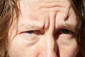 Close-up of caucasian female with furrowed brow in intense sunlight capturing wrinkles and expressions. photo