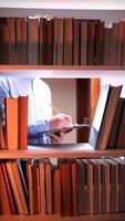 uma pessoa é escrevendo em uma computador portátil dentro frente do uma livro estante video