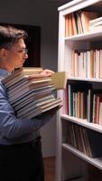 vertical Librarian putting book on shelf in library at night video
