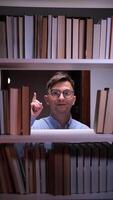 A man in glasses is looking at books in a bookcase video